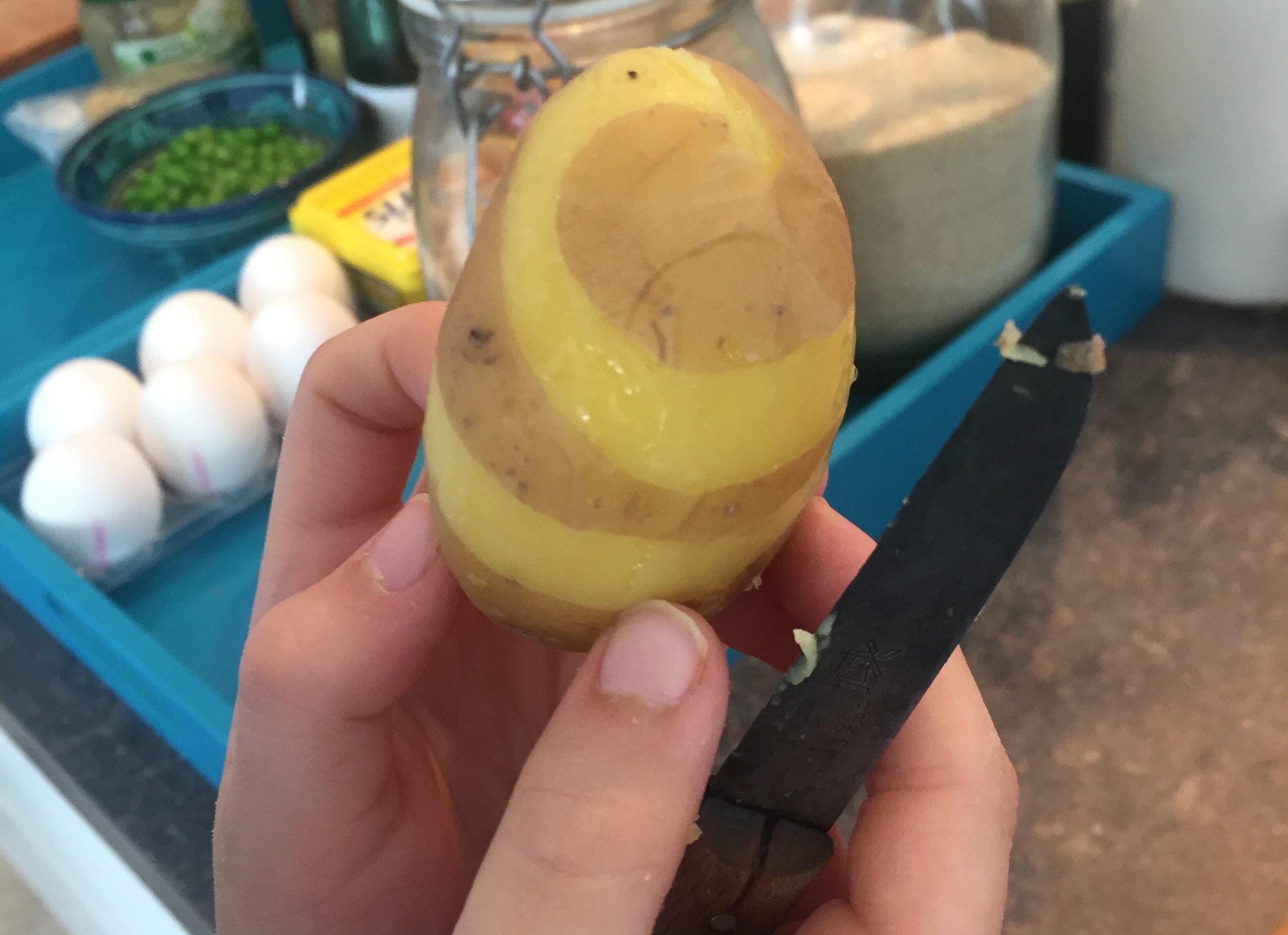 Ein Kind schaelt eine Kartoffel